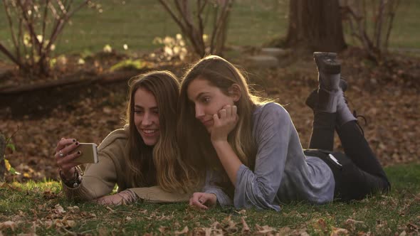 Wide view of twin teenage girls taking photos with smartphone