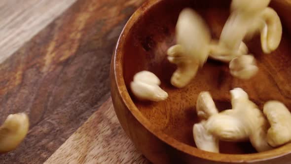 Falling dry cashew nuts in slow motion into a wooden rustic bowl