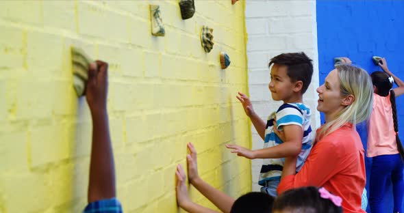 Trainer assisting kids in climbing wall