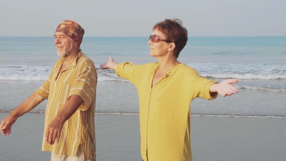 Aged Couple Practicing Yoga on the Beach