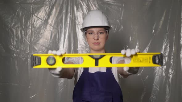 Woman Builder in Blue Overalls and White Hard Hat Helmet with Level