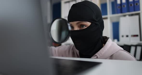 Robber Wearing a Mask and Searching for Information Using Magnifying Glass on Computer in Office