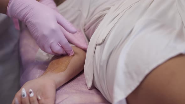 Cropped View of Hair Removal Procedure From Client's Hand