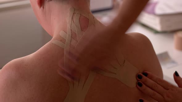 Kinesiologist Applying Kinesiology Tapes on Female Back