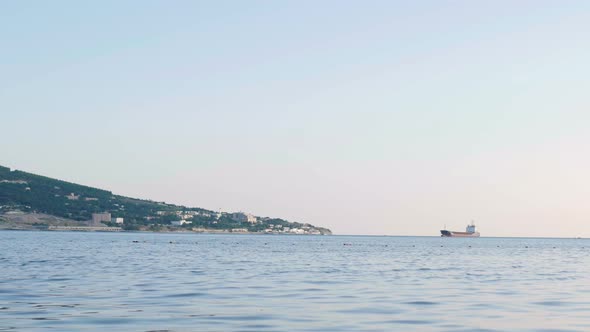 Cargo Ship On The Sea Near A Town On The Mountain