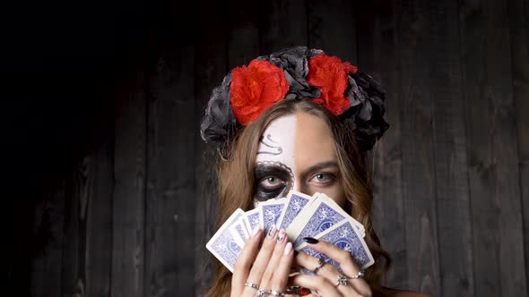 Lady Model with Skull Makeup Shows Cards Against Wooden Wall