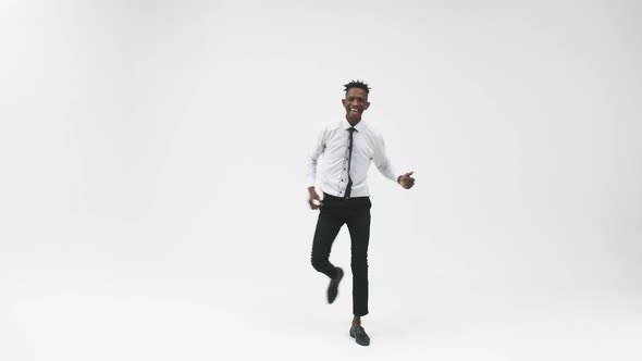 Black Man in an Office Suit Smiles and Dances Against a White Background