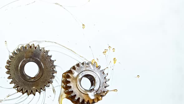 Super Slow Motion Shot of Rotating and Splashing Metal Cogwheels on White Background at 1000 Fps.