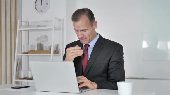 Middle Aged Businessman with Neck Pain Working on Laptop