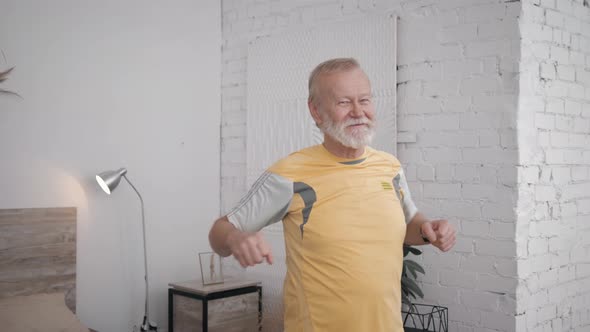 Smiling Grandfather Fan of Sports and Healthy Lifestyle Performs Useful Exercises To Maintain