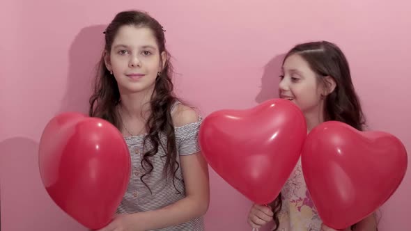 Cute Girls Sisters with Red Heart Balloons on Pink Background