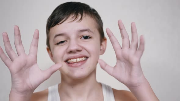 Smiling Boy Waving Arms Showing Gestures of Greeting Goodbye Looking at Camera