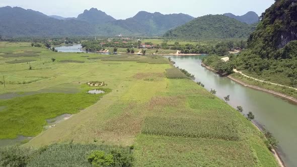 Aerial Motion Over Fields on Calm River Bank Against Hills