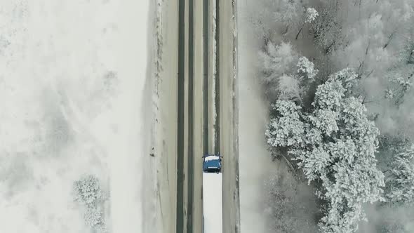 Aerial view of traffic on the road passing through the winter forest