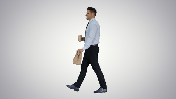 Businessman walking with take away coffee and paper bag