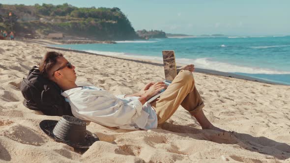 Freelancer Man Working Using Laptop Sitting on the Beach. Freelancer Working on New Startup Project