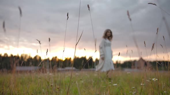 Woman Dancing in Grassy Field in Evening