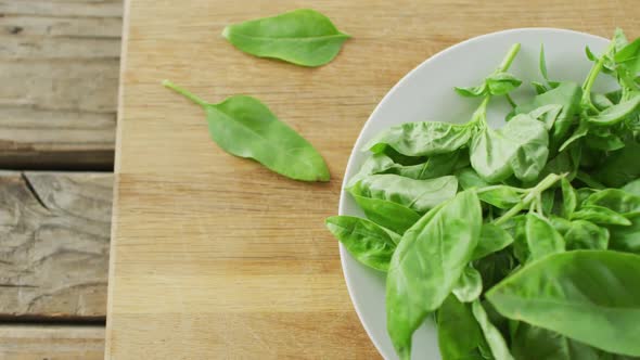 Video of close up of bowl of fresh salad leaves on wooden background
