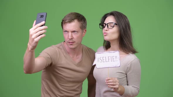 Young Happy Couple Taking Selfie Together Against Green Background