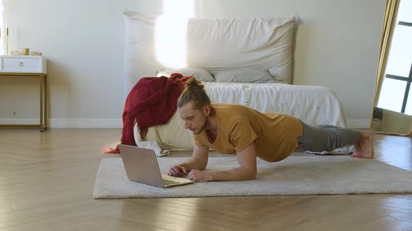 Young Man in Plank Position in Front of Laptop Monitor