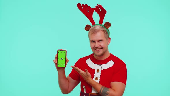 Man in Tshirt Santa Christmas and Deer Antlers Showing Mobile Phone with Green Screen Chroma Key