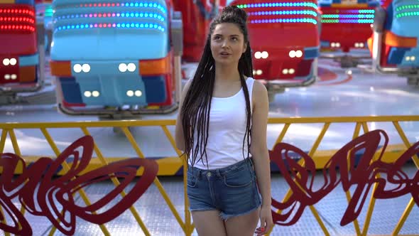 Attractive Girl with Pigtails of Hair on the Background of the Carousel