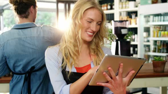 Smiling waitress standing at counter using digital tablet