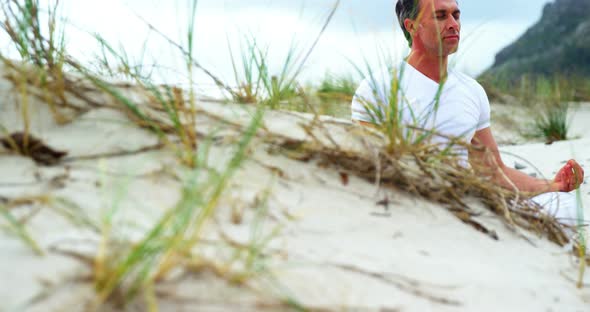 Mature man performing yoga at beach