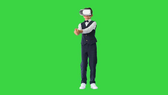 Excited Boy in Formal Wear Playing the Sword Game in Virtual Reality Goggles on a Green Screen