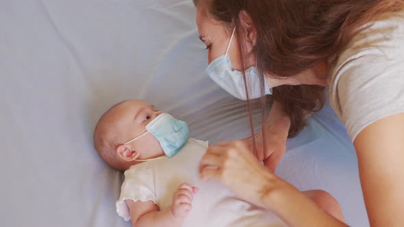 Mom Tries on a Medical Mask for Her Infant Little Daughter. Coronavirus or COVID-19. Cute Little