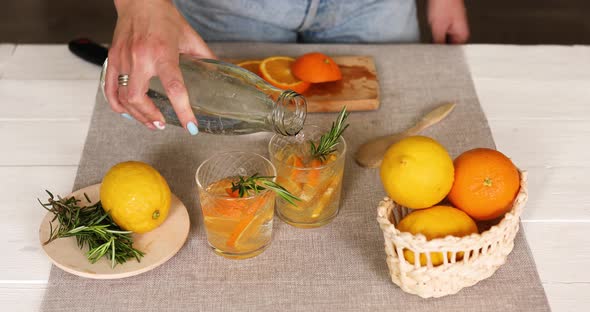 Female hand put pours water in glasses, making fresh lemonade