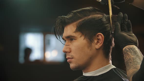 A Young Man Having a Haircut in Barbershop By the Tattooed Barber in Black Gloves - Cutting the Nape