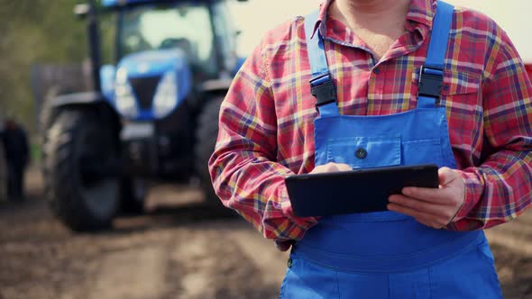 Close-up of Hands. Farmer, in Red Plaid Shirt, Is Typing in Tablet Smth, Against Background of