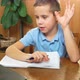 A 7Yearold Schoolboy Writes and Shows a Notebook to the Monitor - VideoHive Item for Sale
