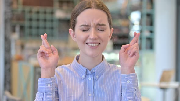 Portrait of Optimistic Young Businesswoman with Fingers Crossed 