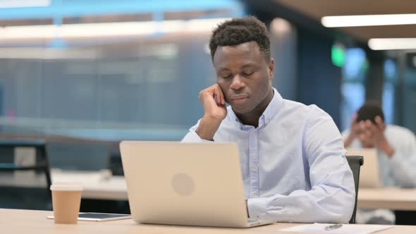 African Businessman with Laptop Taking Nap in Office