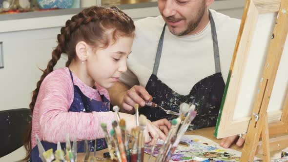 Cropped Shot of a Cute Little Girl Smiling Talking To Her Dad Mixing Paints at Art Class