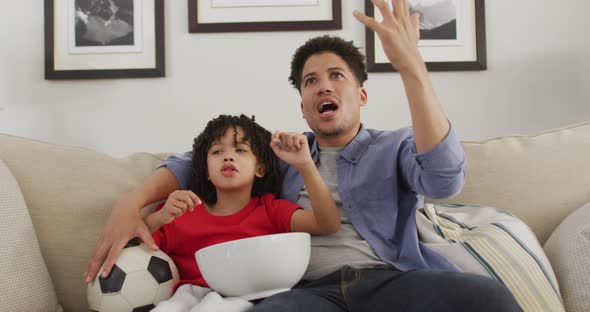 Happy biracial man and his son watching football match together