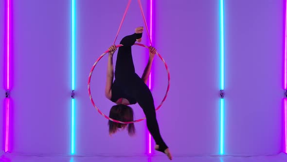 An Athletic Aerial Girl Acrobat in a Black Leotard Performs at a Height and Performs Acrobatic