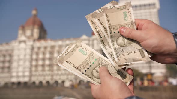 A Man Considers Indian 500 Rupees on Mumbai Street