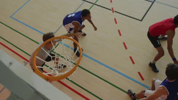 Overhead view of african american male basketball player scoring goal against diverse players