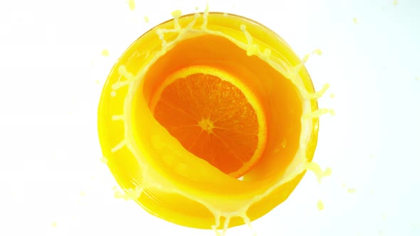 Super Slow Motion Shot of Orange Slice Splashing Into Orange Juice Isolated on White at 1000Fps