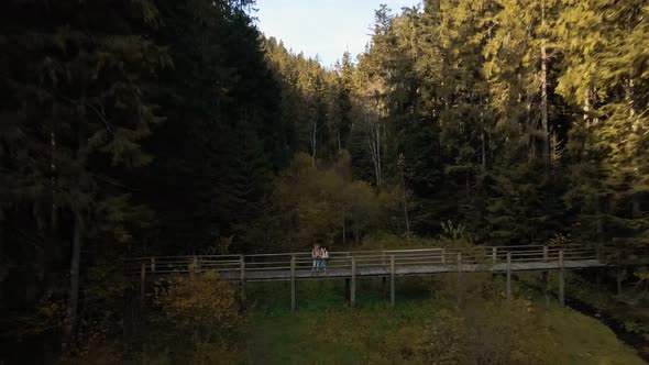 Aerial Slow Motion View of Couple Hikers Man and Woman on Shore of Beautiful Famous Mountain Lake