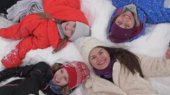 Two Women and Two Teenage Girls Lie in the Snow and Someone Is Pouring Snow on Them From Above