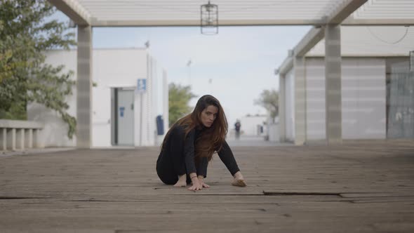 Young Woman Sits on Wooden Bridge and Begins Crawling Toward Camera
