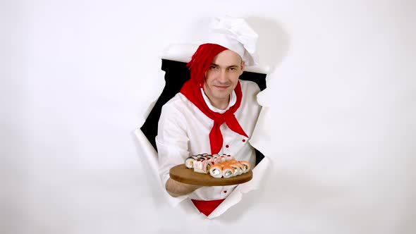 Young Man Dressed As Chef Holding Wooden Board with Sushi Rolls