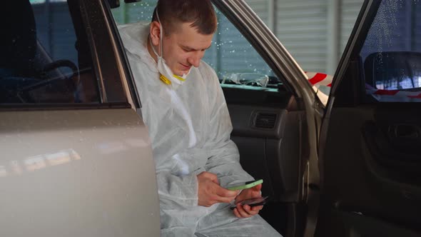 Man Medical Worker Doctor Dressed White Protective Overalls Sitting Car Resting Using Smartphone