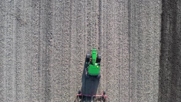 Top Down Aerial View of Tractor Plowing Dry Land at Farming Field on Hot Sunny Day, High Angle Drone