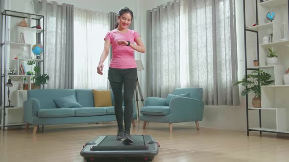 Front View Of Asian Woman Training On Walking Treadmill At Home