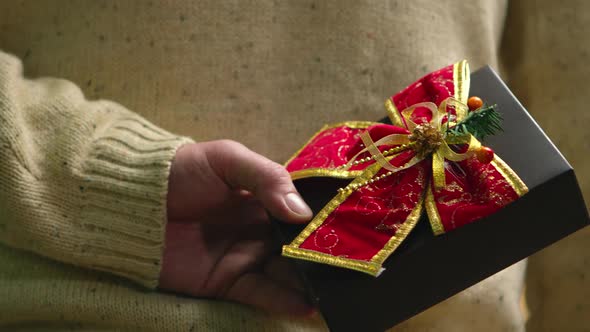 Close Up of Young Man Holding Present Behind His Back